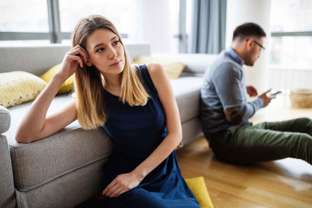 neglect in marriage, the man is holding the phone and the woman is sitting facing the other side